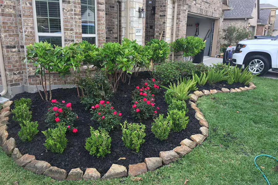 Front yard landscaping with colorful flowers, shrubs, and a stone border, enhancing curb appeal with well-manicured plants.