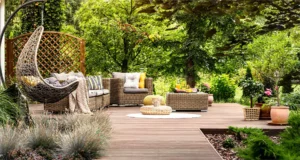 Backyard patio with wicker furniture and hanging chair surrounded by vibrant greenery in Little Elm, TX for summer lawn care and landscaping ideas