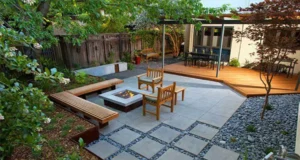 Modern backyard landscape design in McKinney TX featuring fire pit, patio seating, wooden deck, and stone pathway