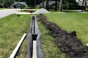 French drain installation trench with gravel and drainage pipe preventing yard water pooling and erosion in a residential lawn in Frisco, TX